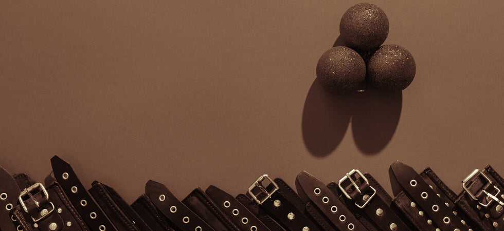 sepia tone holiday image of cuffs lines up in a row below three christmas ornaments