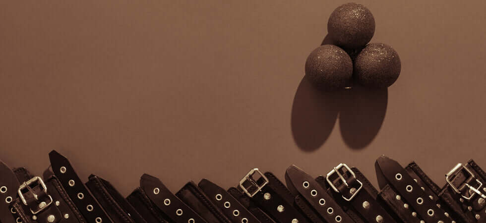 sepia tone holiday image of cuffs lines up in a row below three christmas ornaments