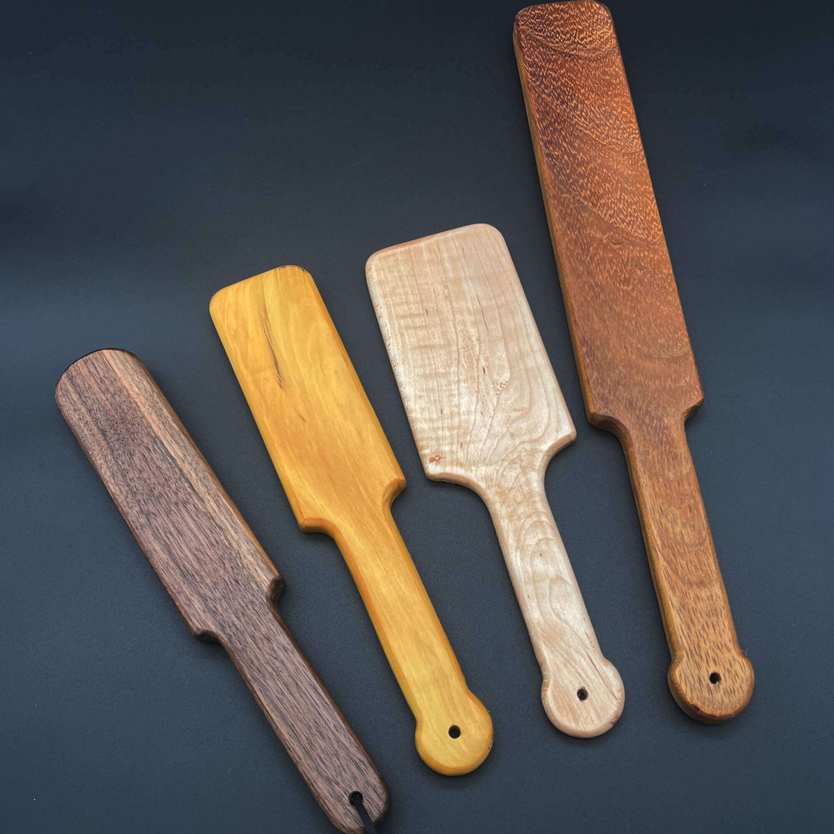 Collection of four wooden paddles showcasing Basic Paddles in various finishes and shapes.