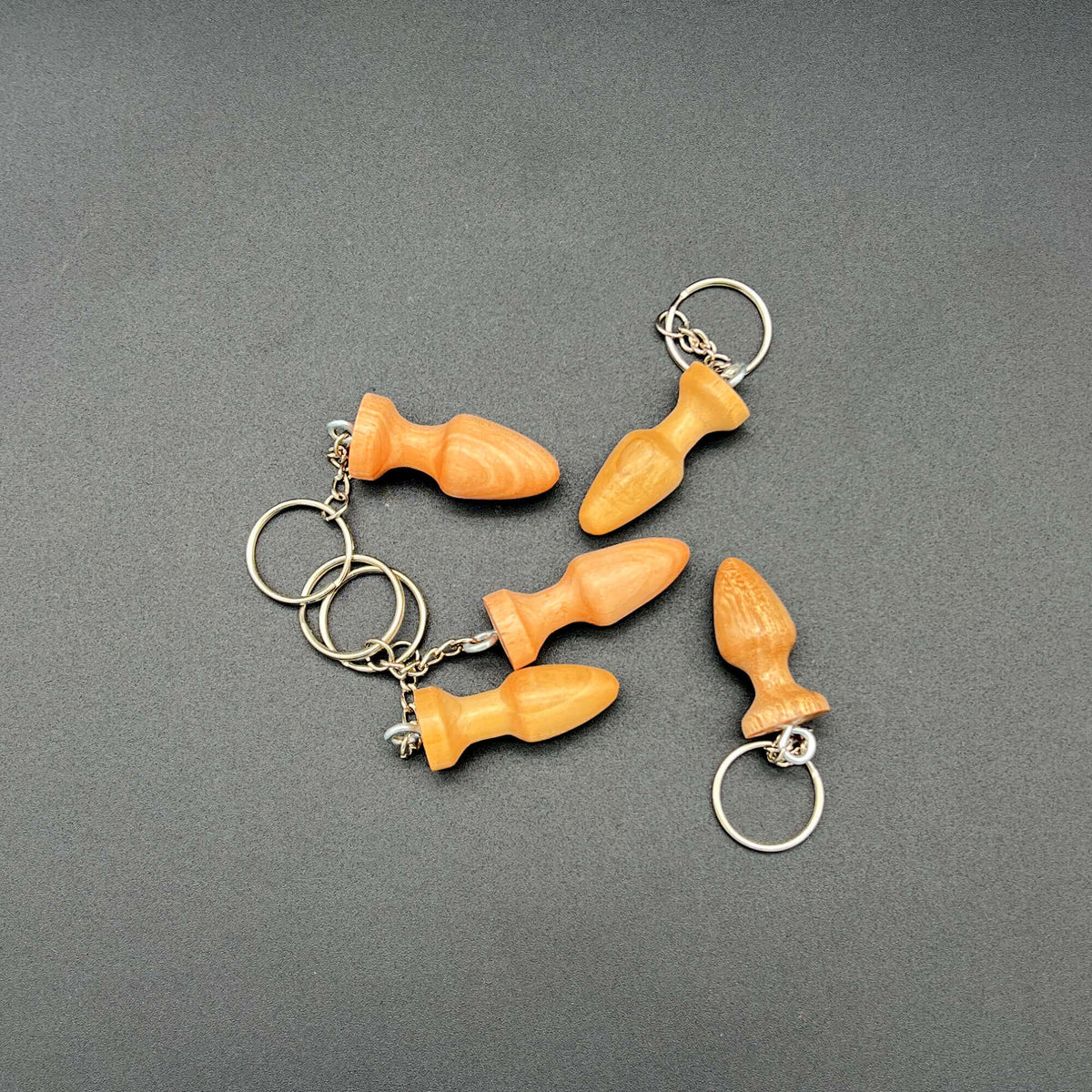 Butt Plug Keychain collection featuring multiple vibrant keychains in an array of styles on a grey background.