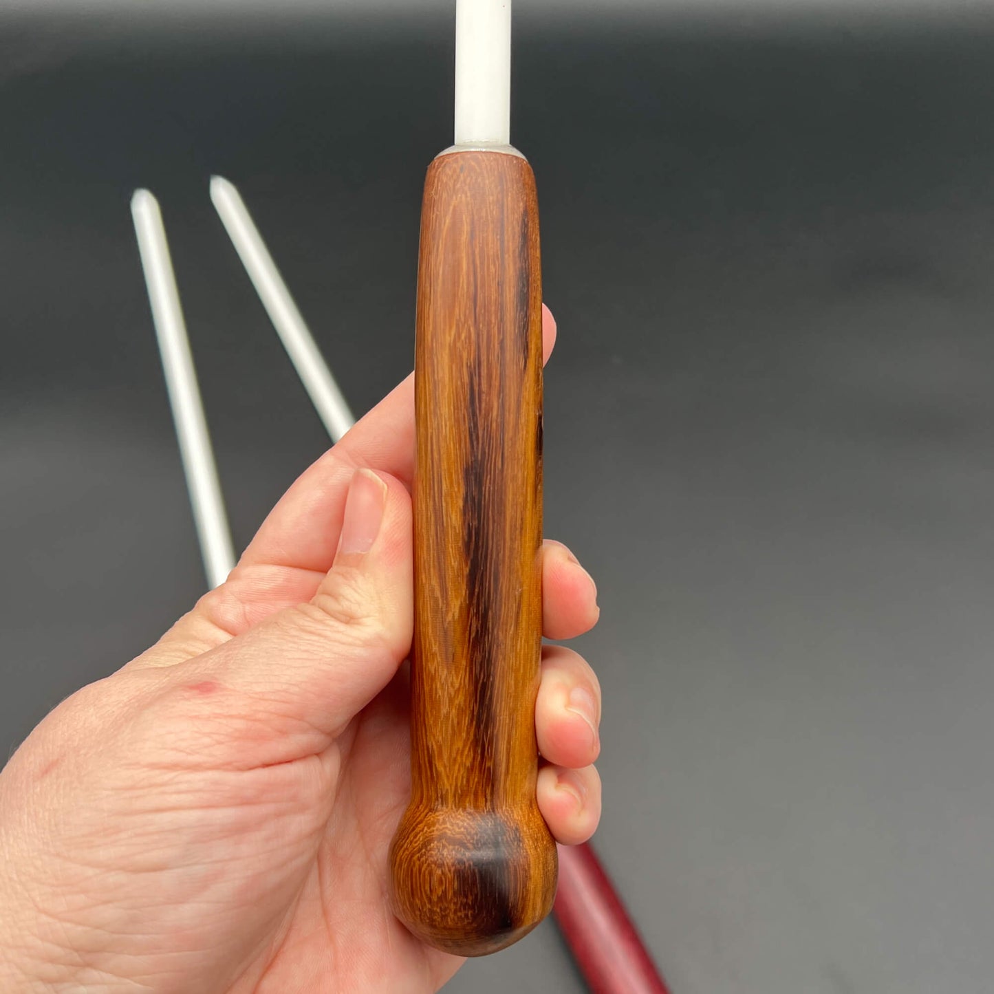 3/8 Inch Delrin Cane with Exotic Wood Handle held in hand, showcasing the smooth, shiny finish and sturdy design.