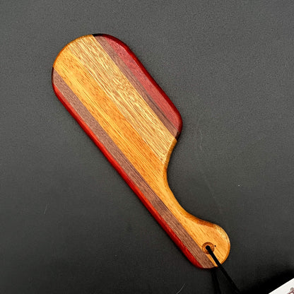 Close-up of a small Pocket Paddle made from Bloodwood, Black Walnut, Black Limba, and Etimoe.
