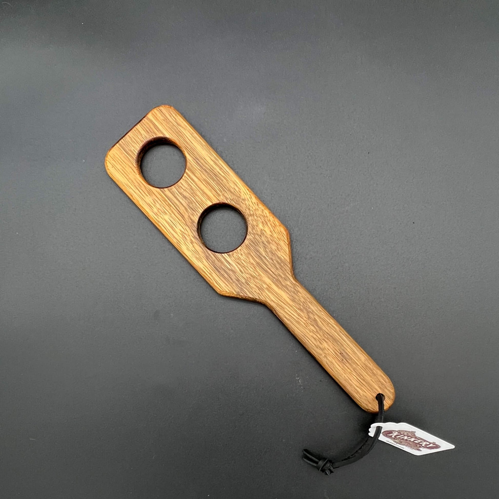 Wooden paddle with two holes on a gray background