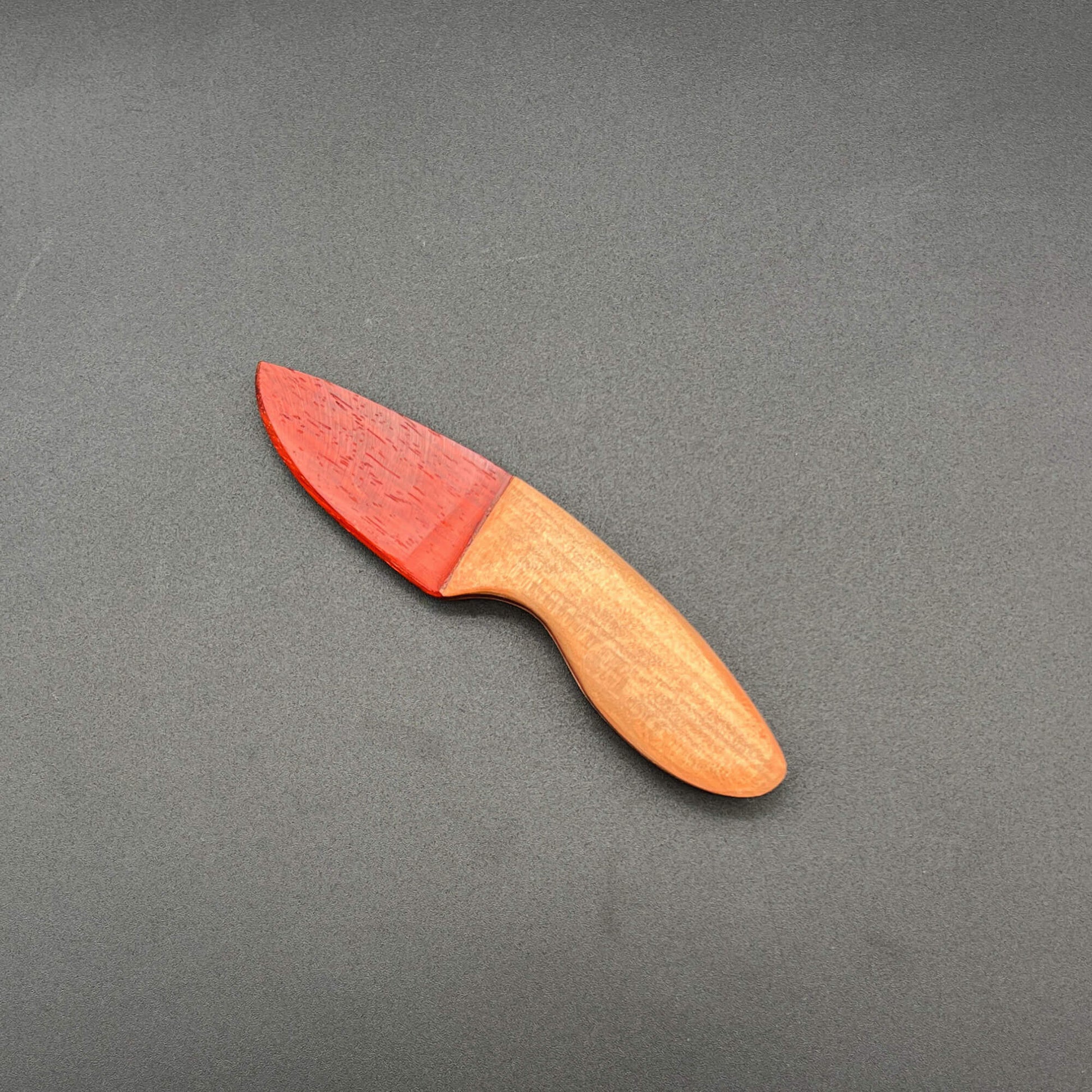 Skinner Wooden Knife with exotic wood blade and light maple handle on a dark background.