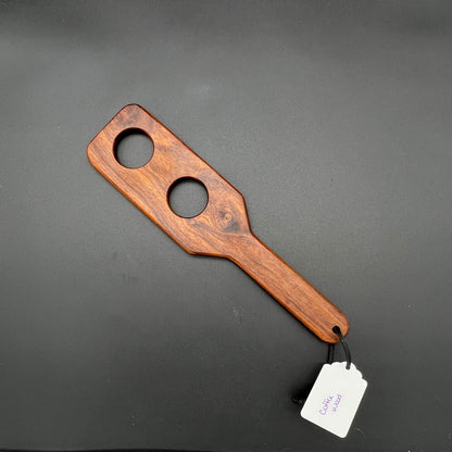 Wooden paddle with two holes on a gray background