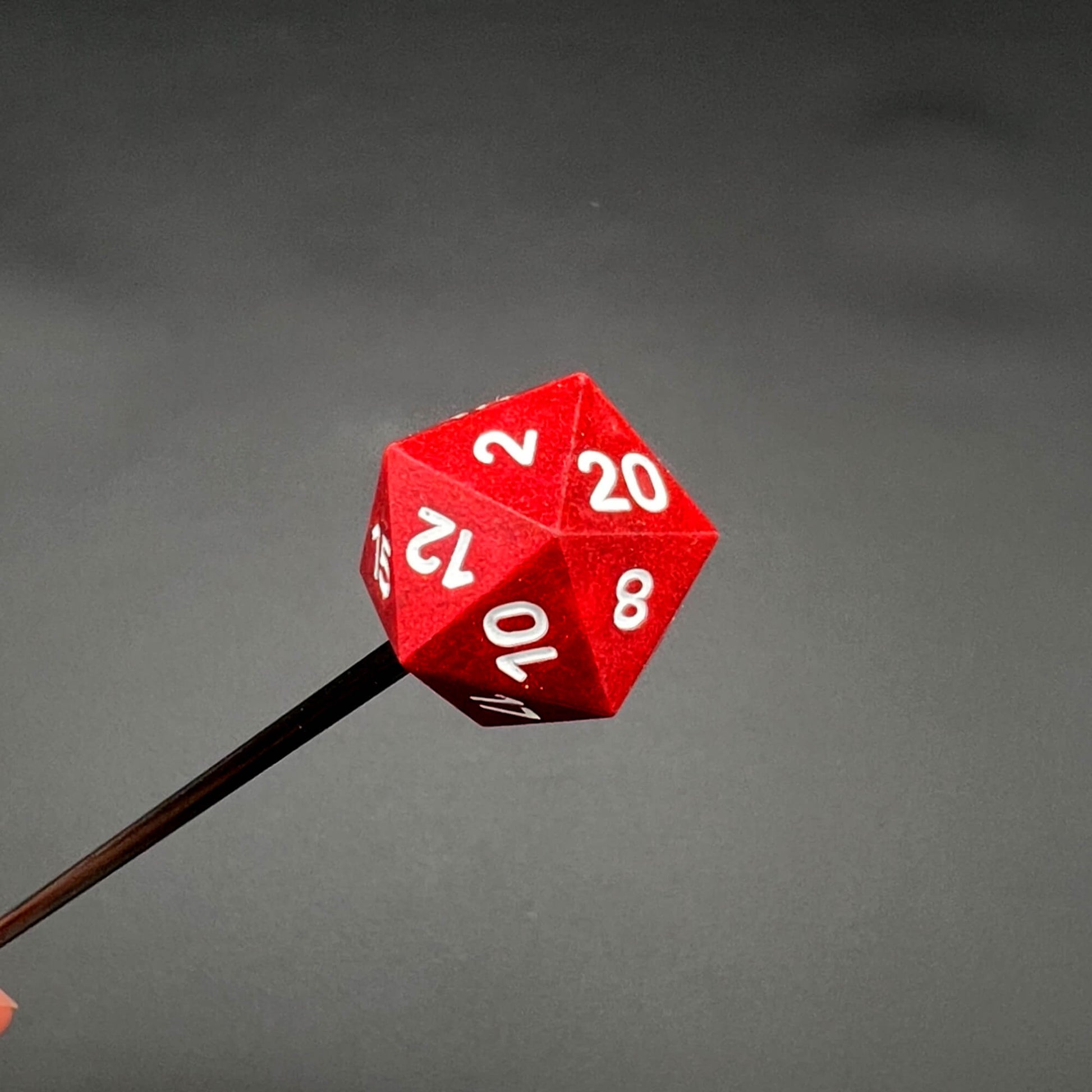 Close-up of a red D20 diabolical stick with white numbers, perfect for TTRPG players and kinksters.