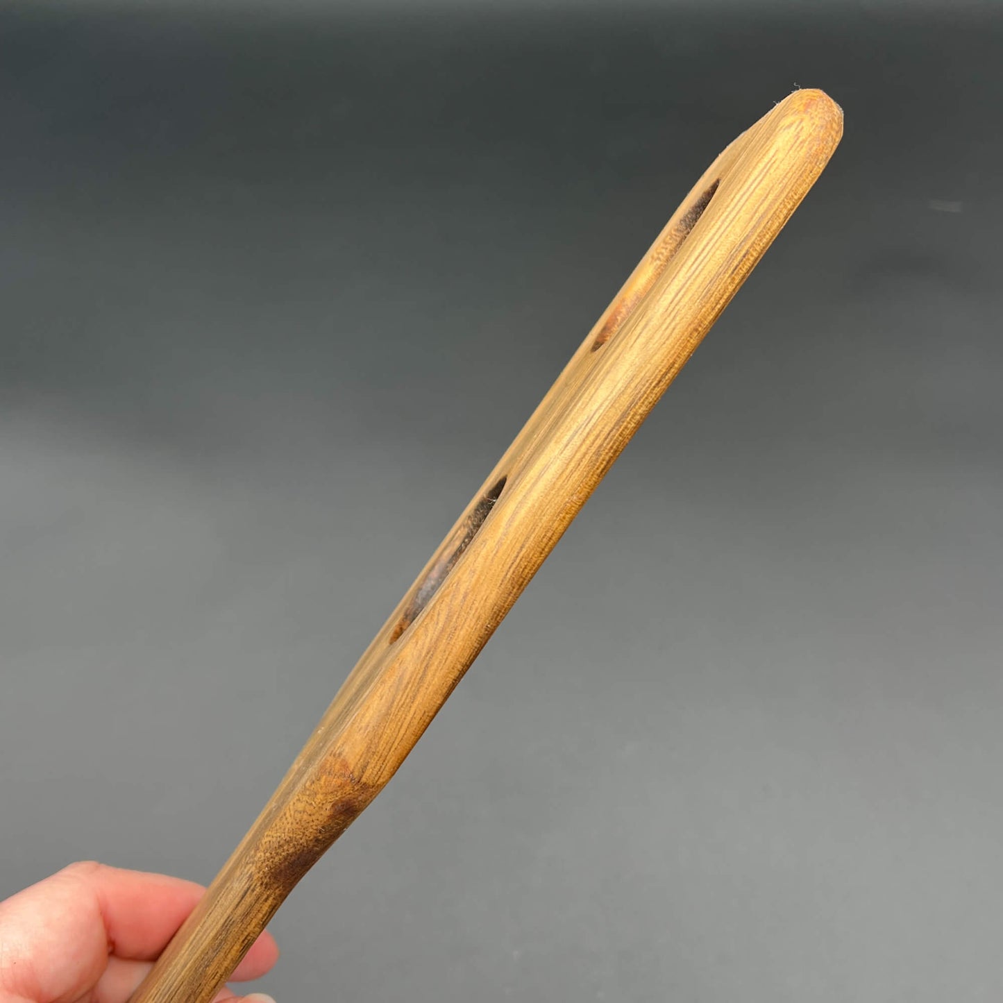 Side view of the Holy Terror wooden paddle showcasing unique shape and grain, designed for impactful sensations.