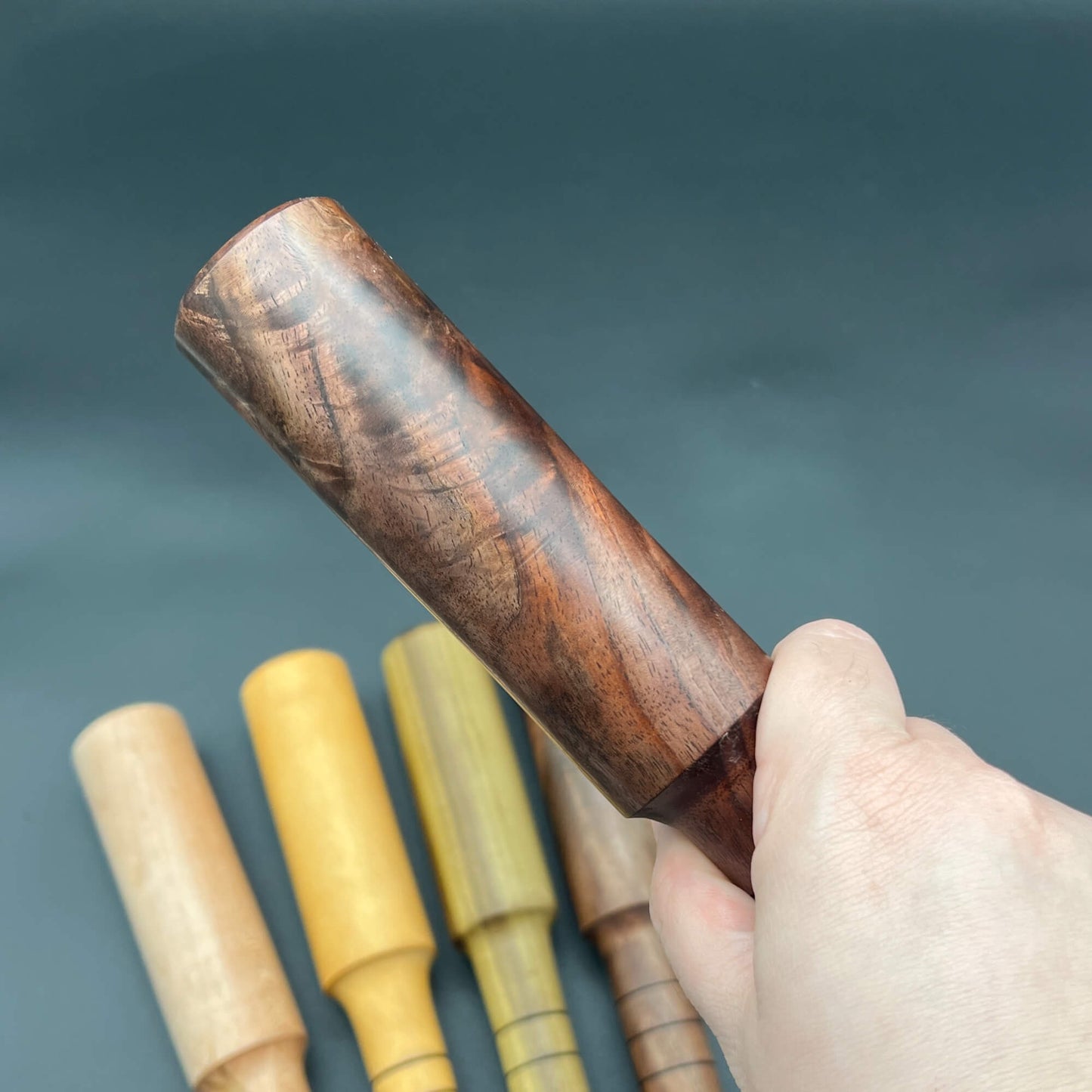 Mini Thumper, a small thuddy paddle, shown in hand with wooden design and various colors in the background.