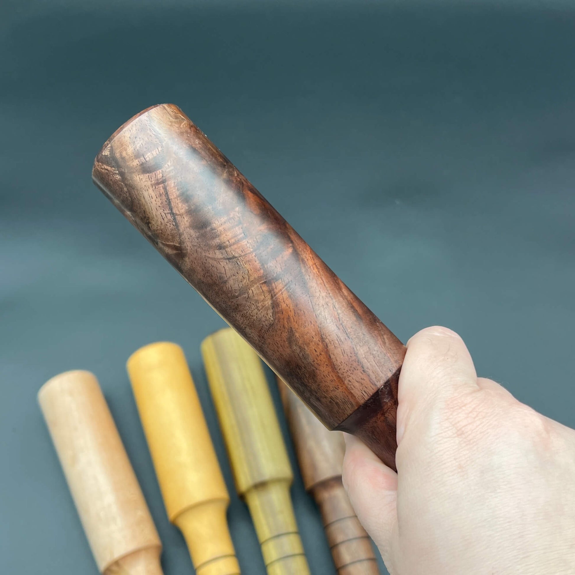 Mini Thumper, a small thuddy paddle, shown in hand with wooden design and various colors in the background.