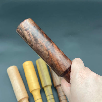 Mini Thumper, a small thuddy paddle, shown in hand with wooden design and various colors in the background.