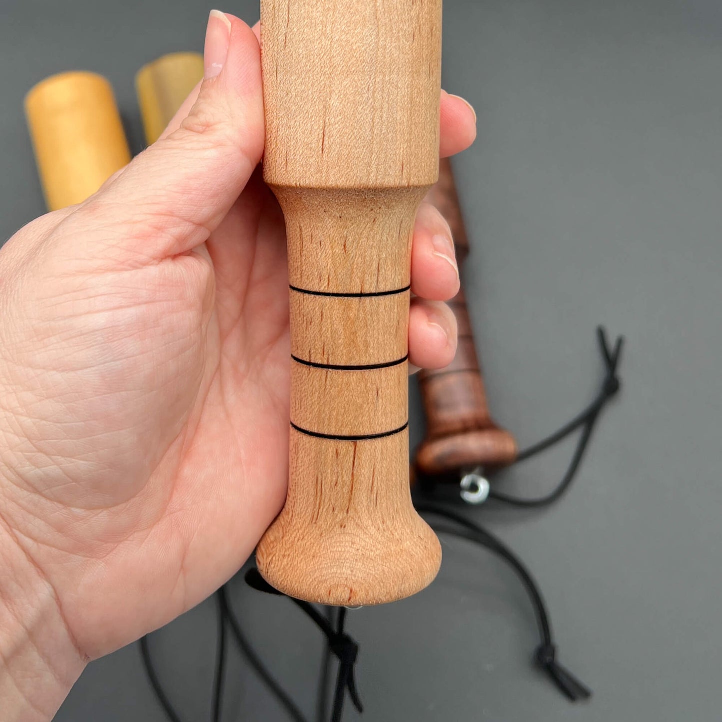 Hand holding the Mini Thumper, a small thuddy paddle for an impactful experience.