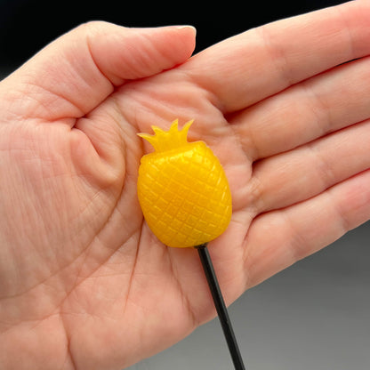 Pineapple Diabolical Sticks held in hand, showcasing the sharp crown and vibrant yellow color of the toy.
