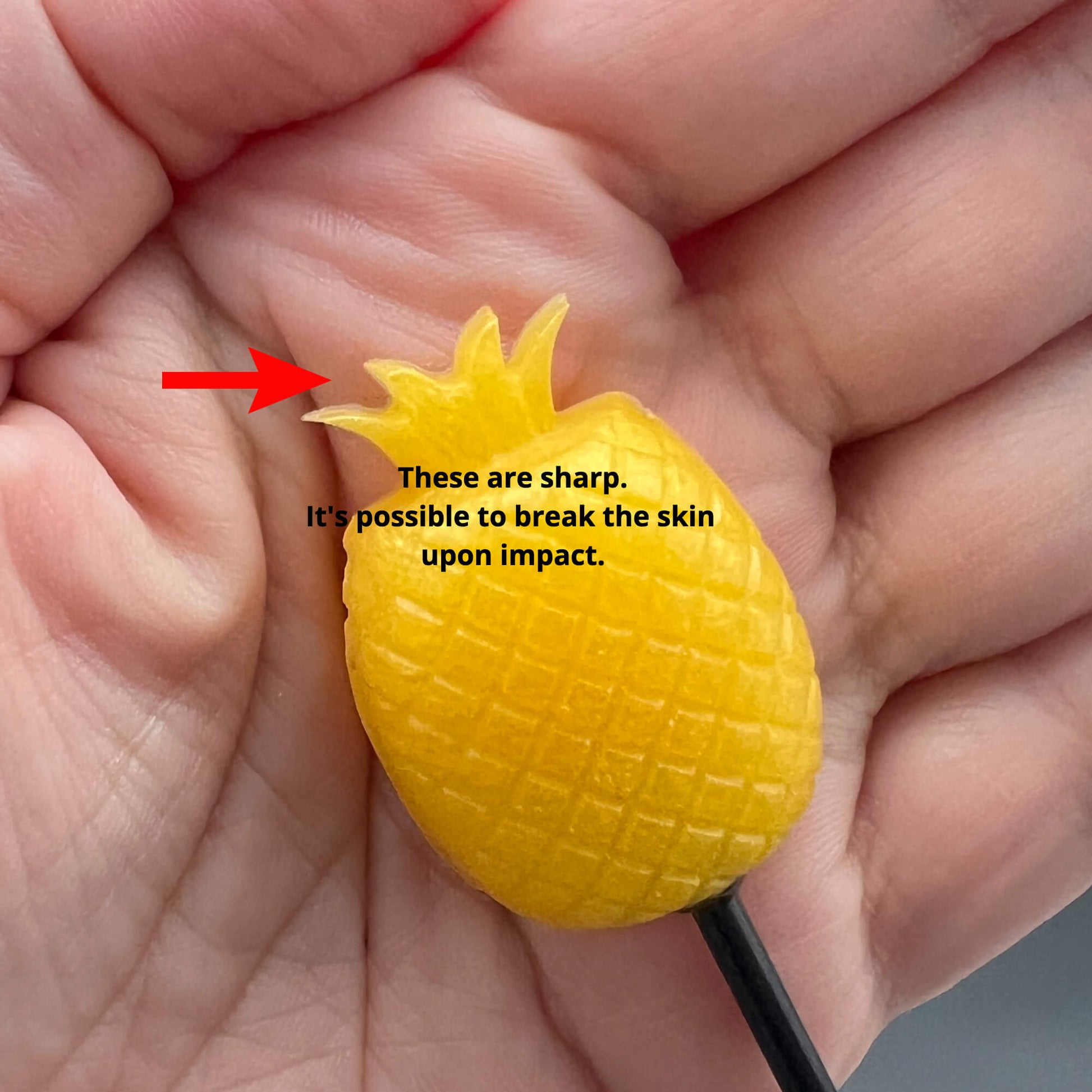 Close-up of a sharp Pineapple Diabolical Stick held in hand, showcasing its potential to break the skin upon impact.