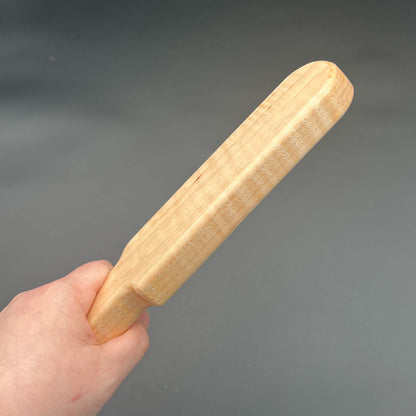 Pounder wooden paddle held in hand showcasing its natural wood grain and finish.
