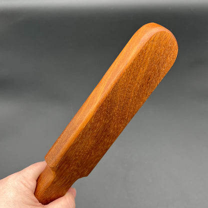 Pounder wooden paddle in natural finish, 12 inches long, simple paddle design, showcasing rich brown wood grain.