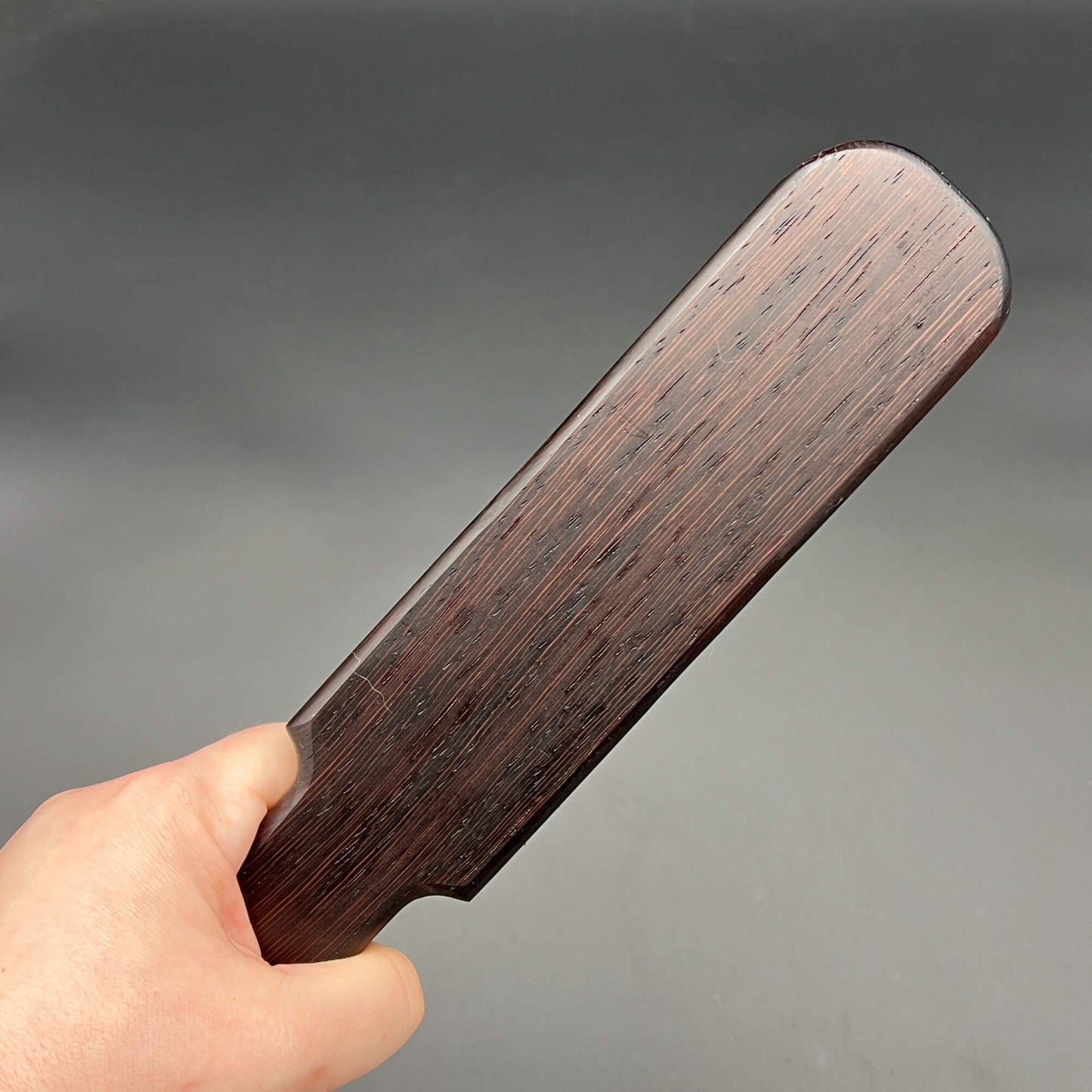Pounder simple paddle made of dark almost black wood, 12 inches long and 2.25 inches wide, finished with natural wax.