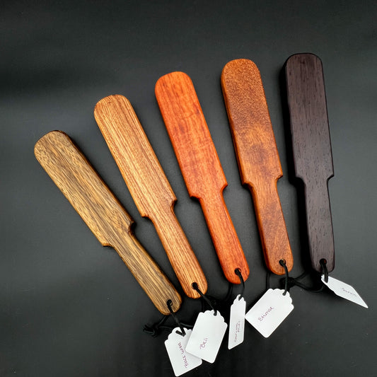 Pounder wooden paddles in various wood shades, simple paddle design measuring 12 inches long. Perfect for impactful use.