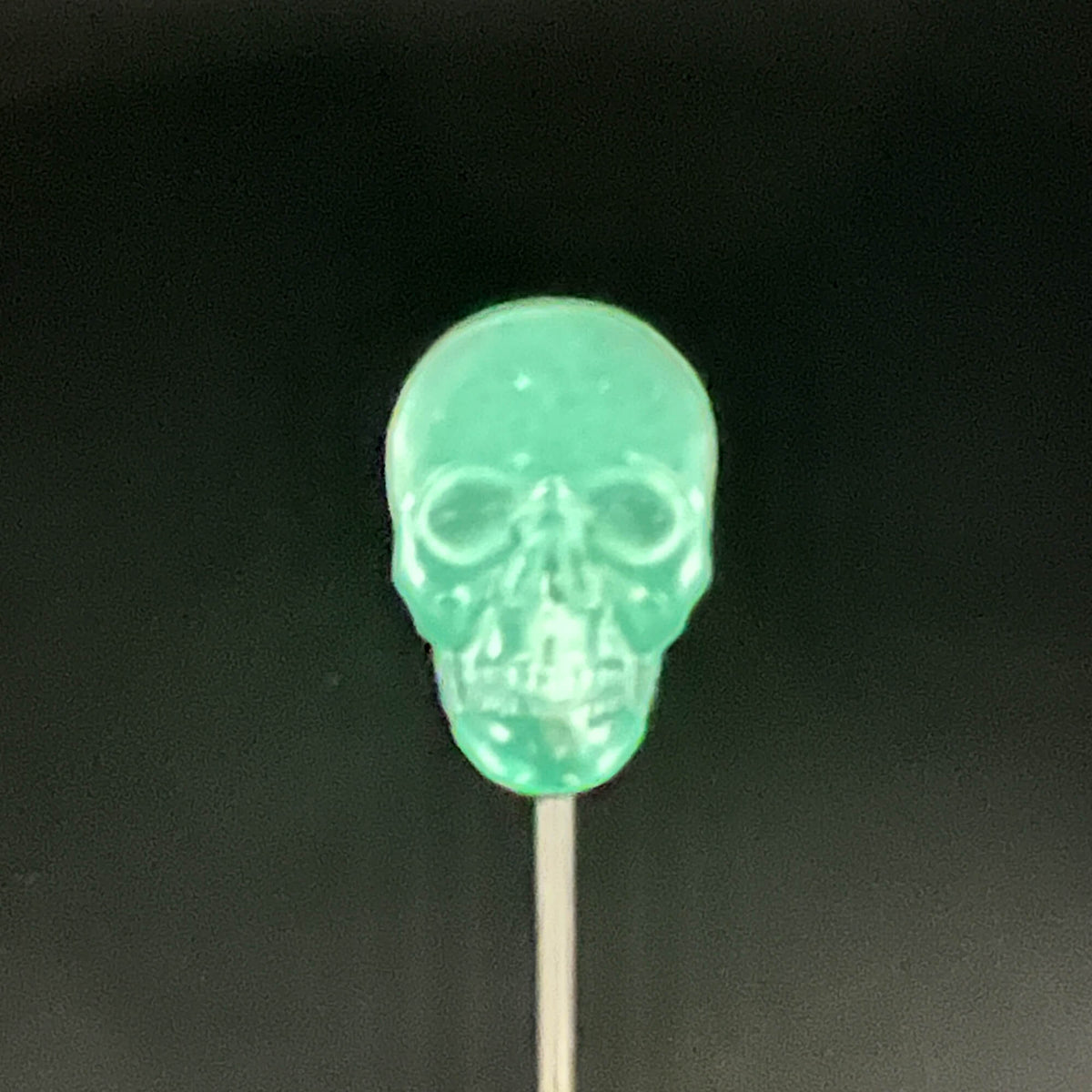 Close up of Skull Diabolical Stick of a green glowing skull tip on black background