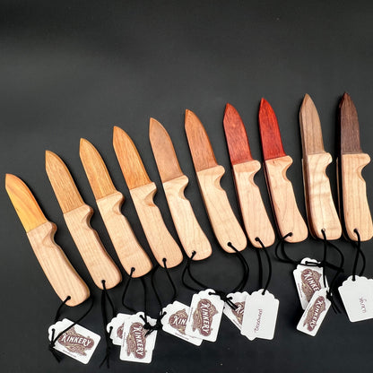 An array of wooden wax play knives with all different woods for the blades; the wooden knife is made in the style of an open switchblade knife.