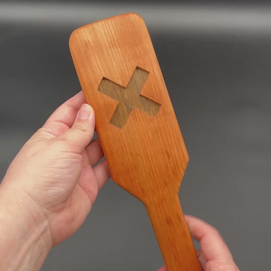 Kayla shows both sides of each XOXO paddle and then smacks each one in her palm. The first one is the Cherry and Black Limba. Next is Cherry and Goncola Alves. Third is Cherry and Black Walnut. For all of these, the Cherry is the outer wood and second wood type is the wood in the center.