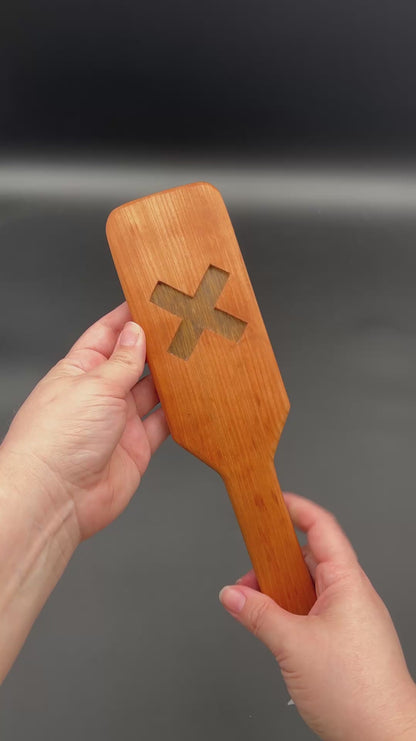 Kayla shows both sides of each XOXO paddle and then smacks each one in her palm. The first one is the Cherry and Black Limba. Next is Cherry and Goncola Alves. Third is Cherry and Black Walnut. For all of these, the Cherry is the outer wood and second wood type is the wood in the center.