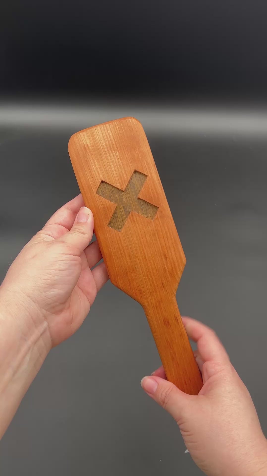 Kayla shows both sides of each XOXO paddle and then smacks each one in her palm. The first one is the Cherry and Black Limba. Next is Cherry and Goncola Alves. Third is Cherry and Black Walnut. For all of these, the Cherry is the outer wood and second wood type is the wood in the center.