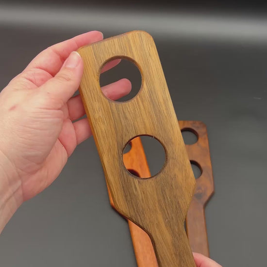 Wooden paddle in hands, showcasing the Holy Terror design with distinctive holes for impact and the smack sound