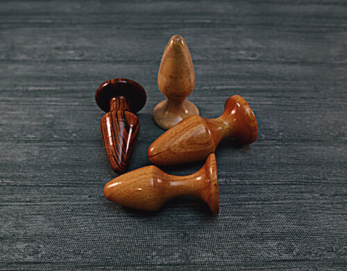 small butt plugs made of exotic wood on gray wooden background