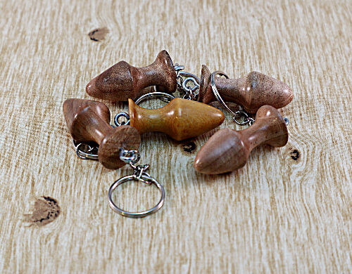 five anal plug keychains lying on a birch wooden background