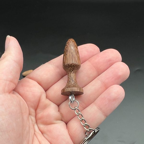 Kayla holding a dark wood mini butt plug keychain