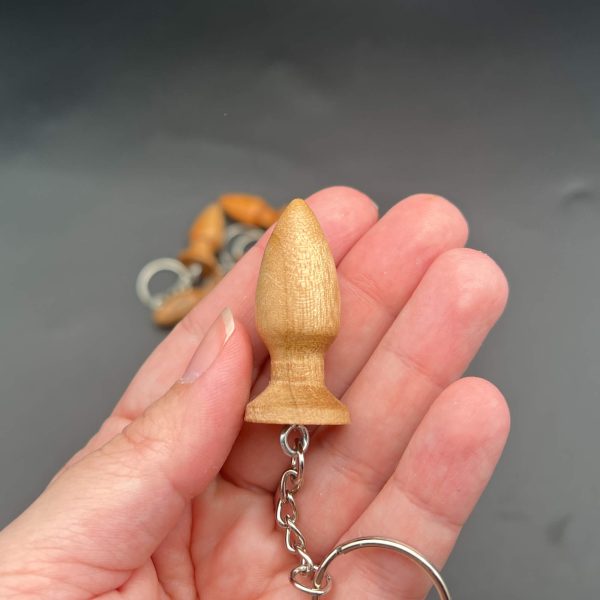 Kayla holding mini butt plug keychain to show size. The plug is about2 inches long and an inch wide at the base