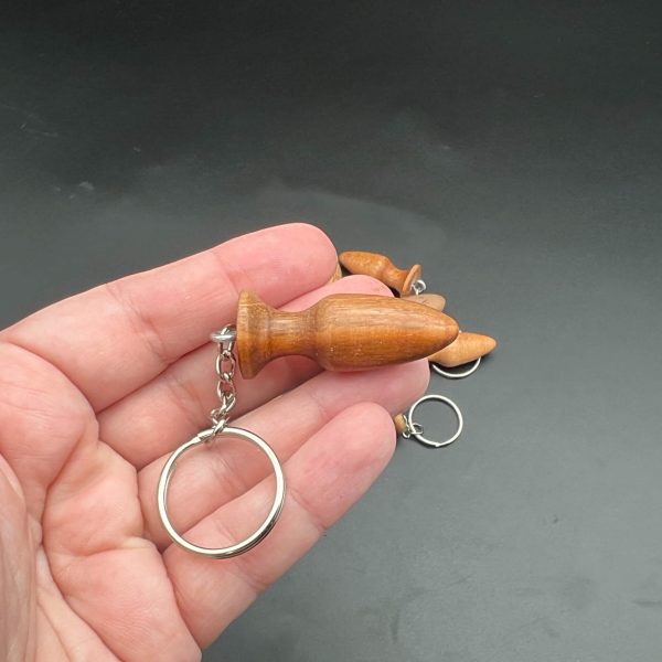 Kayla holding a mini butt plug keychain to the side to show the shape of the plug