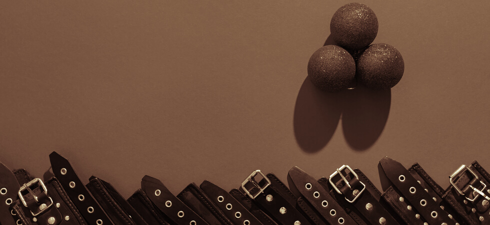 sepia tone holiday image of cuffs lines up in a row below three christmas ornaments