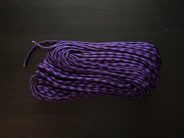 purple and black paracord on dark brown background