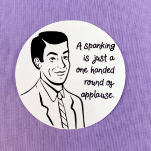 round black and white sticker on purple background. Drawn masculine figure in black, text reads a spanking is a one handed round of applause