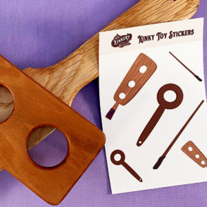 kinky toy sticker sheet next to two wooden paddles