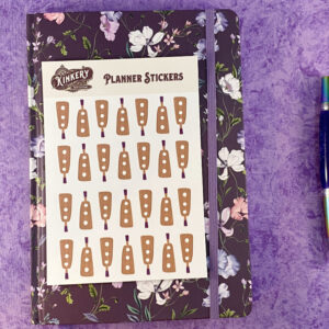sheet of holy terror paddle planner stickers on top of floral purple planner next to turquoise pen on purple background