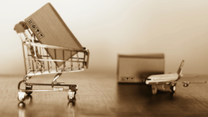 box in shopping cart and box next to airplane as concept for international shipping