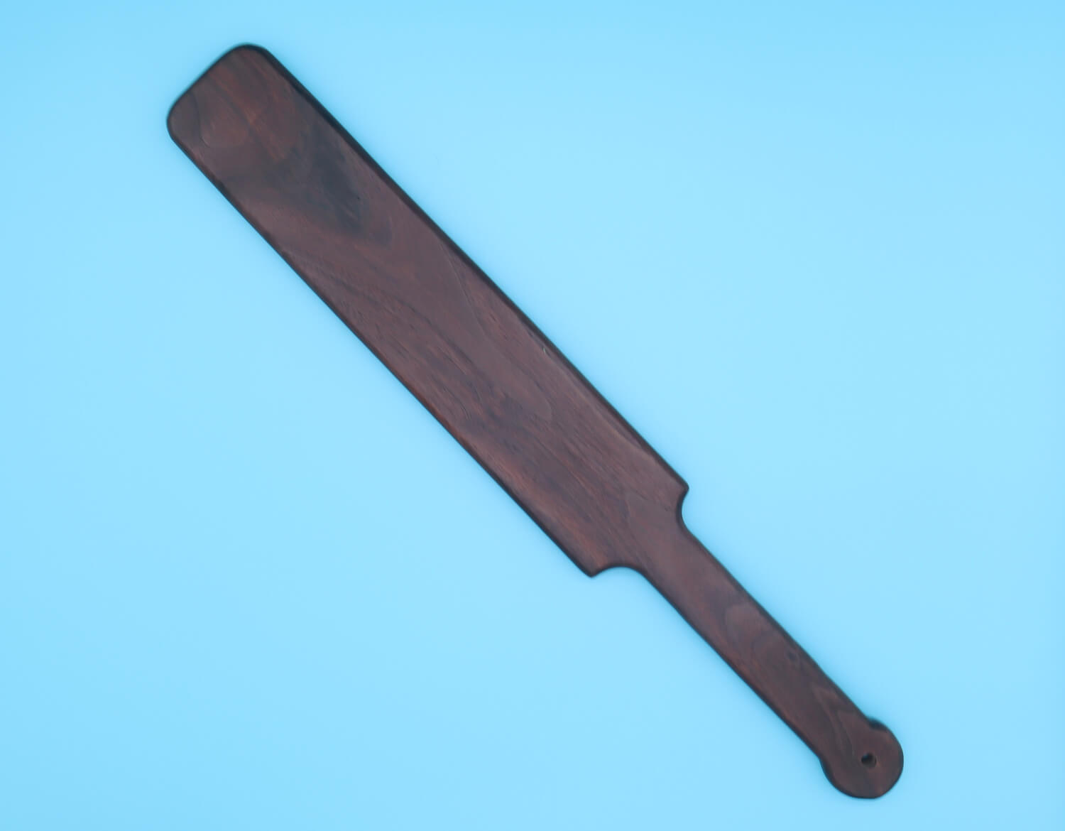 large wooden paddle made of black walnut over blue background