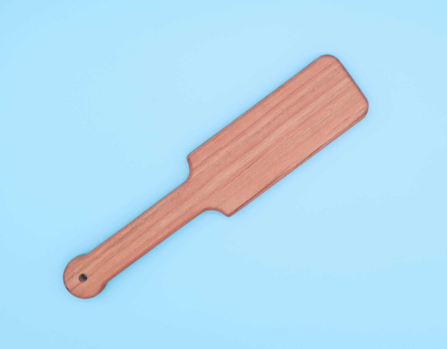 small wooden paddle made with cherry over blue background