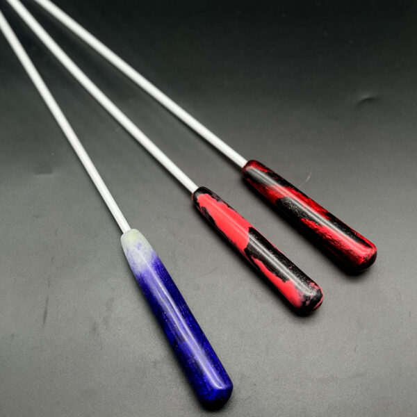 Examples of resin handles for 1/4 inch Delrin canes. Left to right: purple and glow-in-the-dark resin; pink and black resin; and red and black resin
