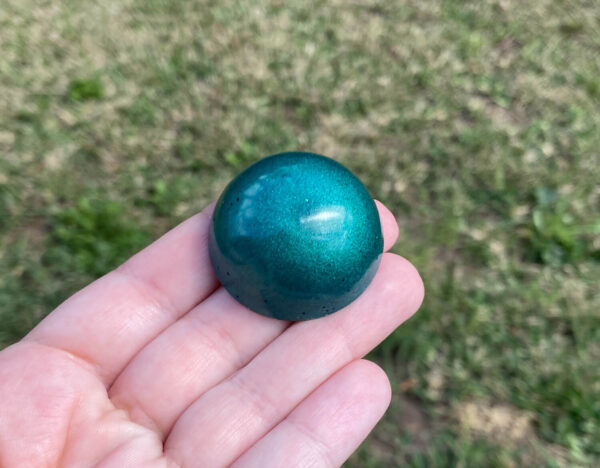 Kayla holding green resin sample in natural light over green grass