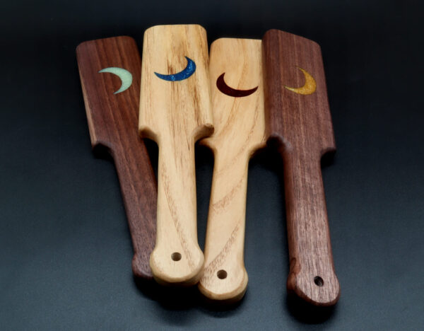 Group of wooden paddles in black walnut and ash with resin inlay crescent moons in a variety of colors