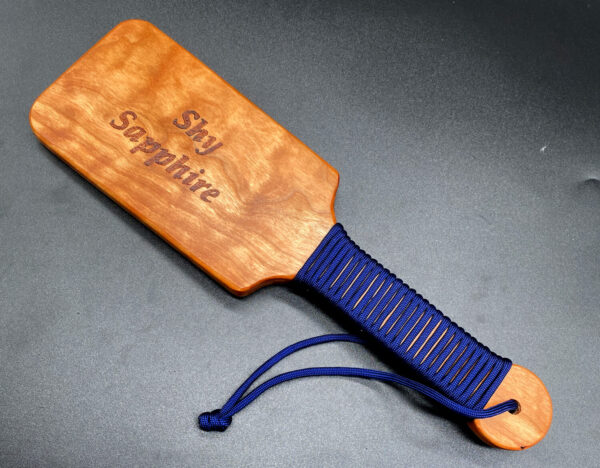 oversized hairbrush paddle with navy blue paracord handle and woodburning that says Shy Sapphire