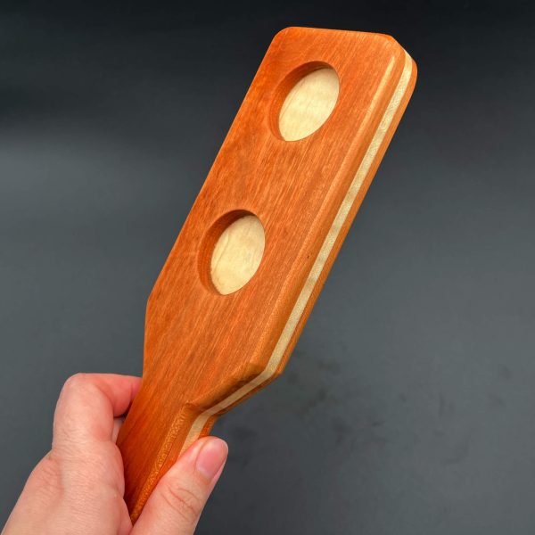 Front side view of the Cherry/Maple paddle showing the two holes cut out of the paddle to reveal the Maple wood in the center