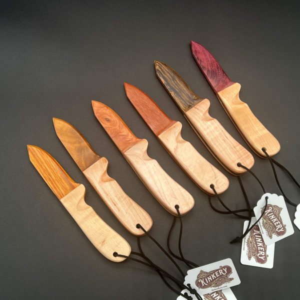 Wooden knives with maple wood handles and a variety of woods for the blades. Left to right: canarywood, black locust, cherry, african mahogany, bocote, and purpleheart