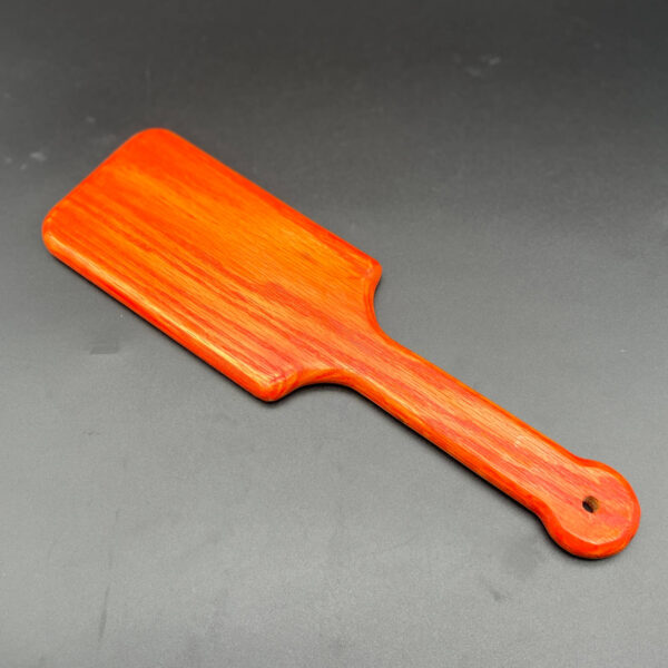 Hairbrush style wooden paddle stained orange with Unicorn Spit