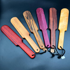 An array of Pounder paddles, left to right: Paduak, Black Locust, Bocote, Purpleheart, Rosewood, and Curly Birch