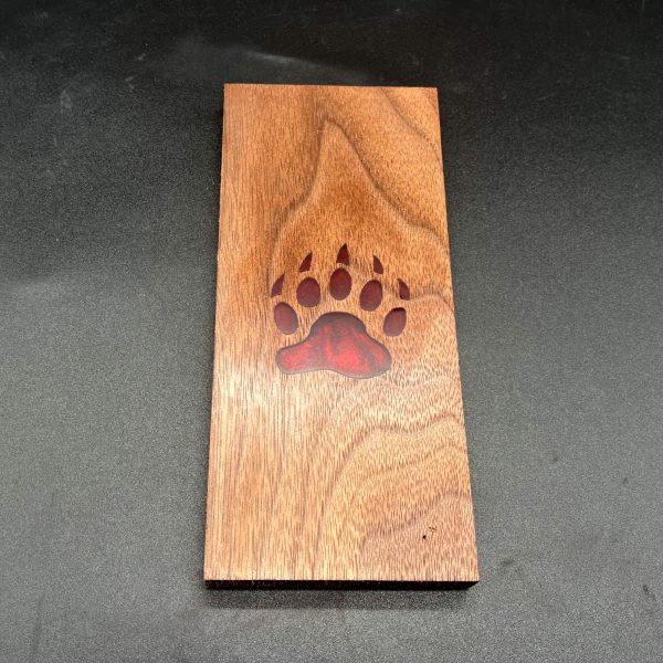red resin bear paw in the center of black walnut wood
