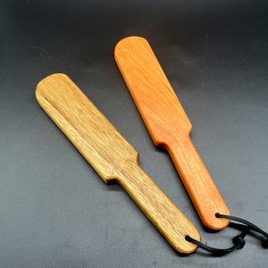 Two wooden paddles called Pounders. On the left, the paddle is made of Black Limba wood. On the right, the paddle is made of Cherry wood.